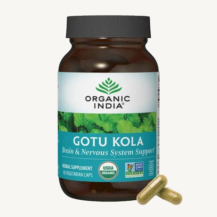 A bottle of Organic India Gotu Kola herbal supplement with two capsules placed in front on a clean white background.